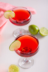Alcoholic cosmopolitan cocktail in glasses and lime on the table vertical view