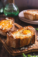 Bread baked with egg and cheese on a cutting board vertical view