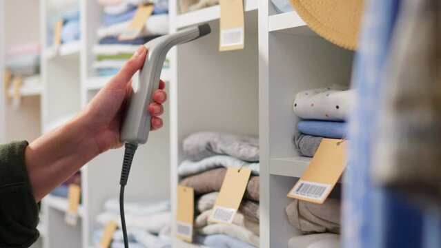 Organized Interior, Business Owner Slowly Scanning a barcode with a scanner. Weighs clothes on hangers, In slow motion Beautiful woman Looks at a shirt in a warehouse, hangers
