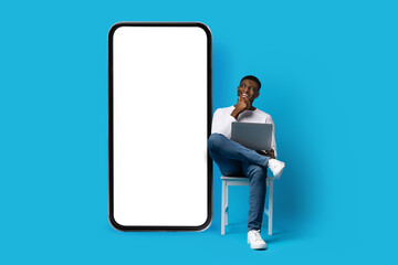excited young black man independent contractor looking at smartphone, mockup