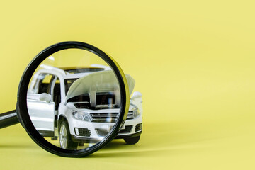 White car and magnifying glass on yellow background with copy space. Concept of car warranty and inspection