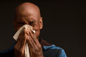 blowing nose after catching the flu and cold with grey black background with people stock image stock photo	