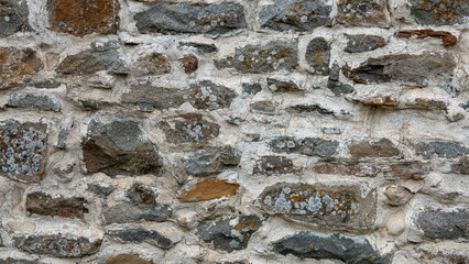 old stone wall background in various colors. The wall of the old historical stone house built with stones one by one