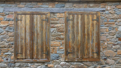 a brick stone house with old retro wooden shutters on the window.. Window frame of  Old italian stone houses