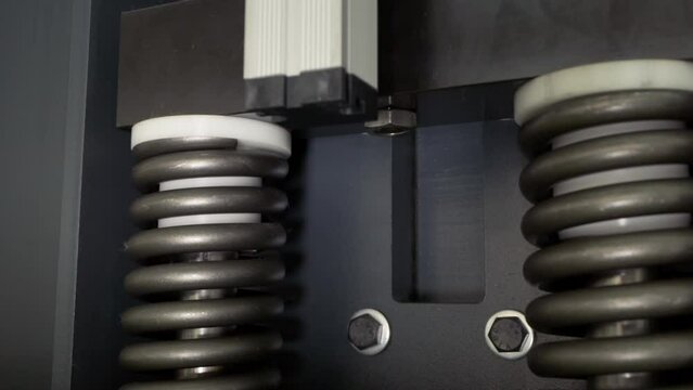 A Close-up of a mechanism inside of the Metalworking Machine. Metalwork Machine is using the support mechanism with hard springs. Metalwork machine is slowly moving up and down using the mechanism.