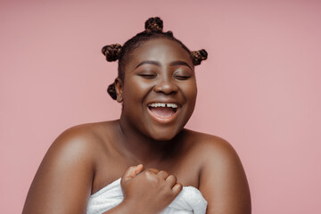 African woman with hairstyle with closed eyes after shower in towel isolated on pink background