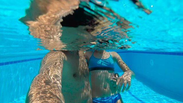 Dad and daughter free time in home pool. A good looking father with her smiling teen makes a video from the swimming pool under sun.