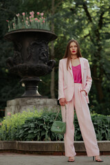Fashionable elegant woman wearing trendy pink suit with classic blazer, satin top, wide leg...