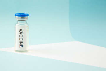 Close up view COVID- VACCINE in a closed ampoule on the right side on blue wave background with free space