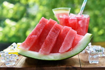 A piece of decoratively sliced watermelon and drink on the table in the garden