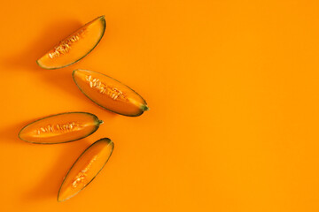 Melon slice on orange background. Creative layout made of fresh melon. Flat lay, top view, copy space, banner