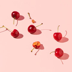 Fresh juicy cherries, creative fruit layout, pastel pink background. 