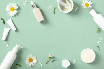 Flat lay composition with chamomile flowers and natural cosmetic products on green background. Skincare concept.