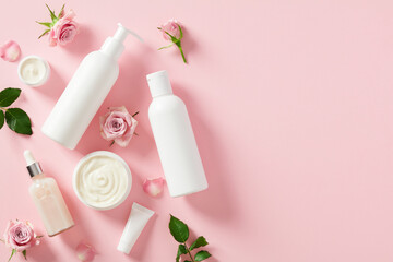 Obraz na płótnie Canvas White shampoo bottle mockup, essential oil, moisturizer cream, rose blossoms, on pink background. Natural skin care cosmetics.