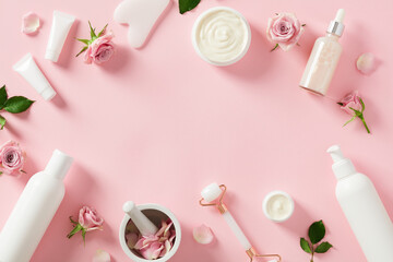 Face skin care routine products with rose blossoms on pastel pink background. Natural beauty...