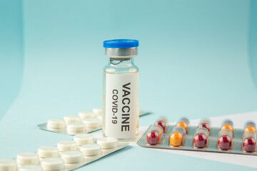 Close up view of vaccine in medical ampoule packed pills capsules on pastel blue background