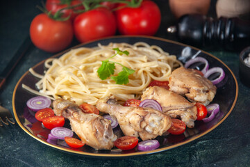 Front close view of raw pastas chickens and vegetables on a plate and cutlery set tomatoes spices wooden hammer cutlery set on green black mix colors background