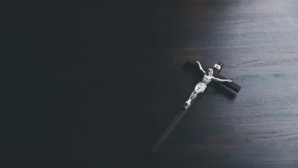 Foto op Plexiglas Wooden Christian cross crucifix on a grunge board background. Wooden Christian cross on grey table against blurred lights, space for text. © doidam10