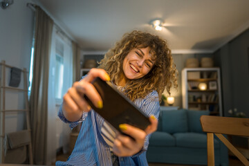 woman caucasian play video games on smartphone mobile phone at home