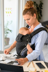 Focused woman with baby examining papers at home