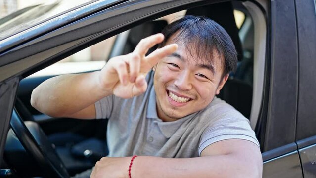  smiling confident sitting on car doing victory gesture at street