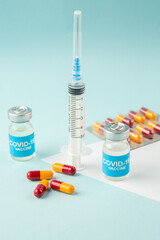 Front view of empty disposable syringe and capsules on a white blank covid- vaccines on blue background