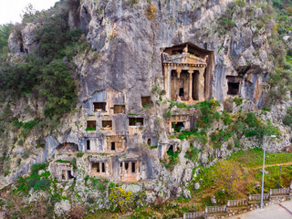 Modern view of remains of ancient Telmessos rock hewn tombs in stone cliff in city of Fethiye,...