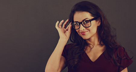 Beautiful thinking happy brunette business woman looking happy in eye glasses and holding spectacles on toned background with empty copy space. Closeup front view studio portrait.