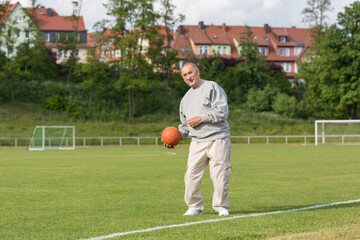 An elderly man goes in for sports on the background of the stadium on a summer evening
