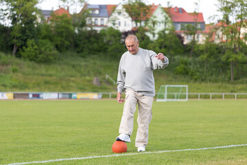 An elderly man goes in for sports on the background of the stadium on a summer evening