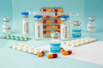 Front view of vaccine in medical ampoules packed pills and capsules for Covid- on blue background