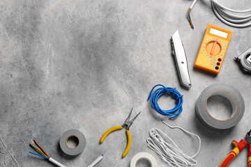 Wires and electrician's tools on grey table, flat lay. Space for text