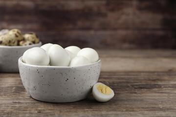 Many peeled hard boiled quail eggs in bowl on wooden table, closeup. Space for text