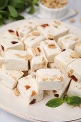 Pieces of delicious nutty nougat on plate, closeup