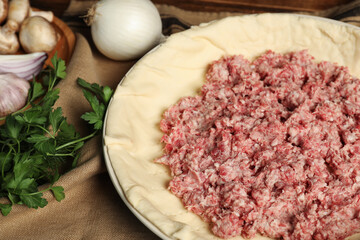 Raw dough and ingredients on napkin, closeup. Baking meat pie