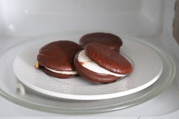 Tasty sweet choco pies on plate in microwave