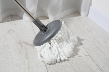 Cleaning white parquet floor with mop, closeup