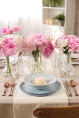 Stylish table setting with beautiful peonies and golden cutlery indoors