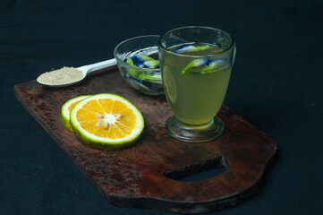 it's a photo of an orange juice extracted from a telecast glass of transparency. Around it were a board, a bowl of betel nut, a spoonful of sugar and lemon slices