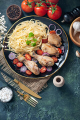 Overhead view of tasty pasta meal with chickens and vegetables spices on a plate flowers spices on nude towel wooden hammer