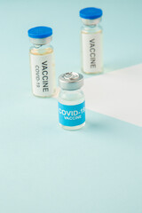 Overhead view of vaccines for treatment Covid- in medical ampoules on white blue background