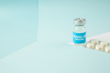 Side view of vaccine in medical ampoule packed pills on the left side on pastel blue background