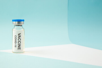 Top view COVID- VACCINE in a closed ampoule on the right side on blue wave background with free space