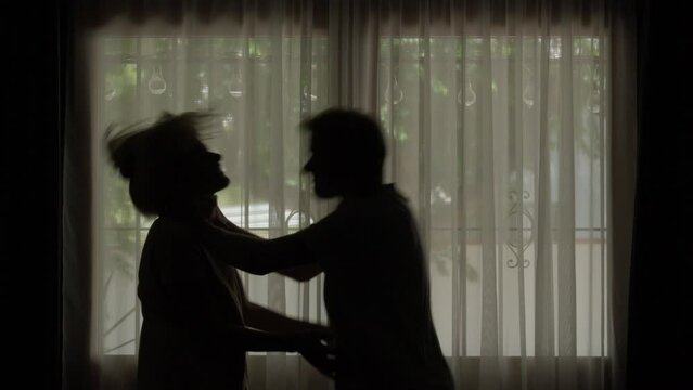 silhouette man choking a woman, strangling, about to slap her, against window background