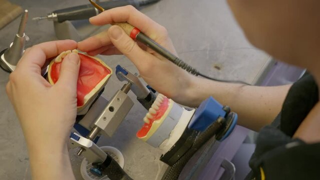 Stomatology Specialist Arranging Artificial Teeth On Denture. Specialist Uses Wax To Attach Fake Teeth To Denture. Specialist Checks Bite Of Denture. Dental Materials Production. Replacement Teeth