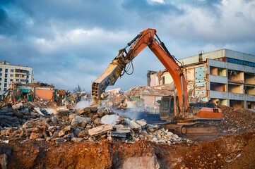 Fototapeta premium Excavator with hydraulic chews breaks beam of concrete