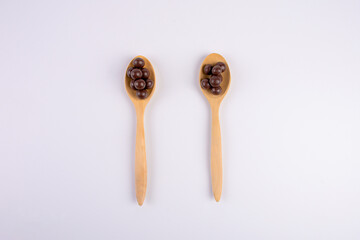 Chocolate balls on wooden spoon on a white background. 