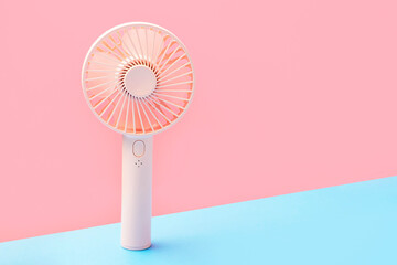 Small portable mini fan on blue and pink background close-up. © TATIANA KIM