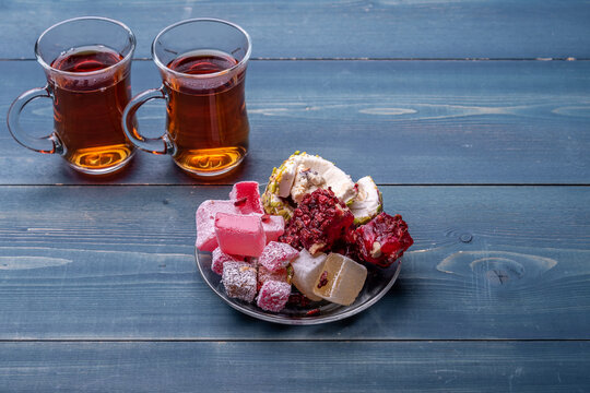Turkish delight, lokum in a plate on a wooden desk against the armudu with turkish tea.