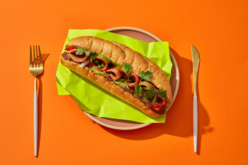 Top view of Vietnamese bread with ham, rolls and pate placed on a green paper on round dishes....